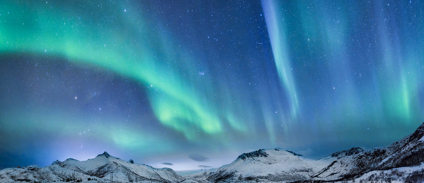 Tre seilbåter som seiler på vannet i en fjord med snødekte fjell i bakgrunnen