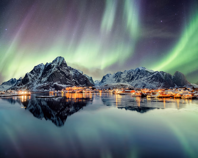 En seilbåt på mørkt hav under grønt nordlys og stjernehimmel i Lofoten