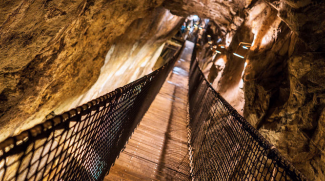 Smal trebro med nettinggjerde gjennom en steinete grotte