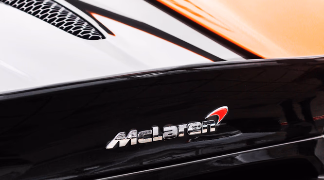 McLaren-logo på sportsbil med hvit og oransje lakk og bikubemønstret ventil